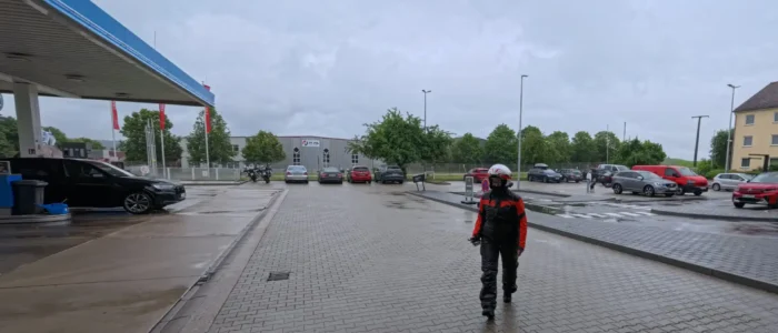 Person an Tankstelle bei Regen